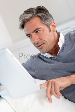 40-year-old man at home using electronic tablet