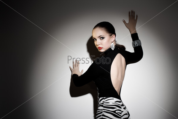 Young gorgeous woman posing against the wall, dramatic lighting, stock photo