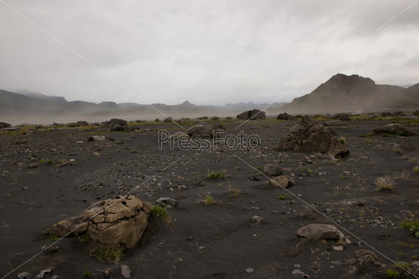 Rugged mountain landscape with dry riverbed and dust rising