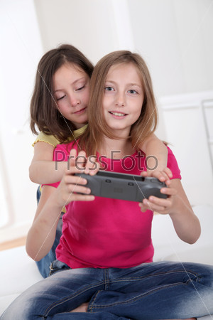 Young girls playing with gaming console on sofa