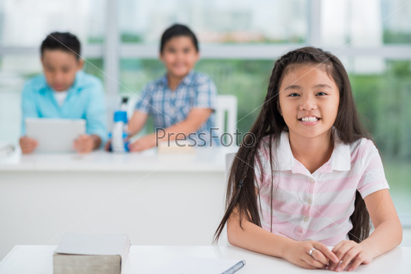 Smiling Vietnamese schoolgirl at her desk in the class