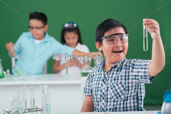 Happy excited boy looking at the test tube with chemical reagent