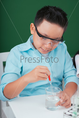 Vietnamese boy working with reagent in the chemistry class