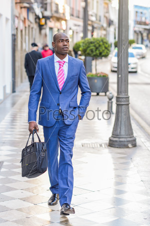 Portrait of a black business man walking on the street with a modern briefcase