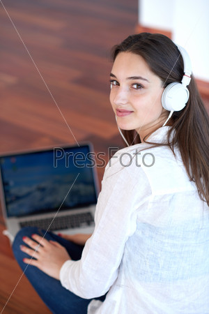 beautiful young woman relax and work on laptop computer modern  home office while listening music on white headphones