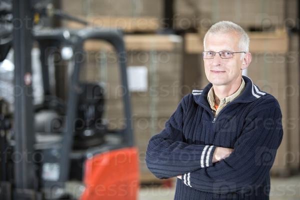 Portrait of confident male worker standing arms crossed at distribution warehouse