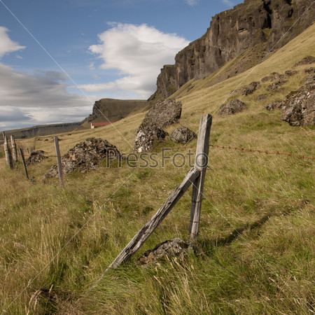 Rural farmland pasture on mountainside with wire fence post