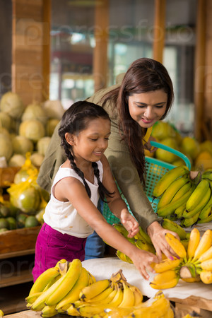 Indian mother and daughter choosing ripe bananas at the fruit market