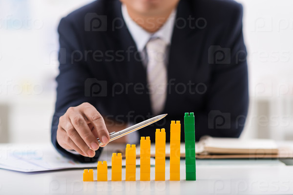 Businessman using pen to indicate ascending bar graph
