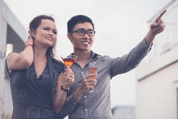 Vietnamese young man showing something to his girlfriend at the party