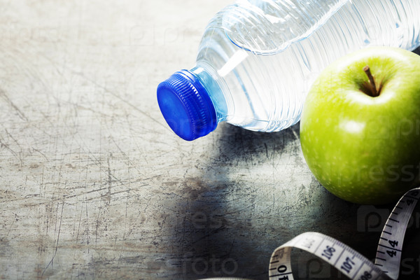 Green apple, water and measuring tape. Health, sport and diet concept