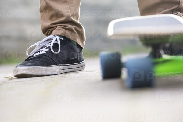 Low section of man with skateboard on footpath