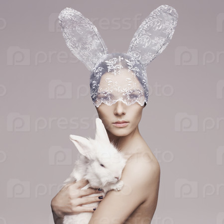 Studio fashion portrait of beautiful lady with white rabbit