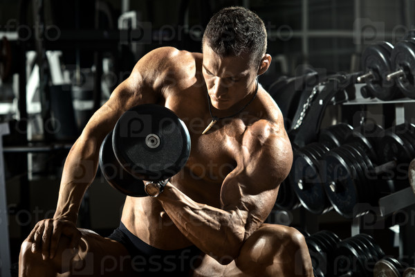 Very power athletic guy bodybuilder , execute exercise with dumbbells, in dark gym, stock photo