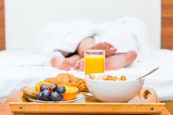 couples feet luxuriate in bed and a tray of food