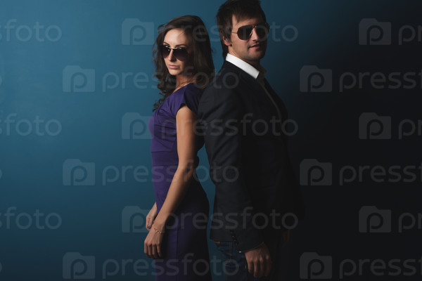 Perfect spy couple man and woman in glasses  standing back to back posing