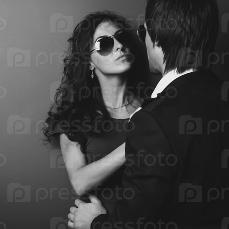 Stunning girl in glasses next to wall and her man in front of her. Black and white.
