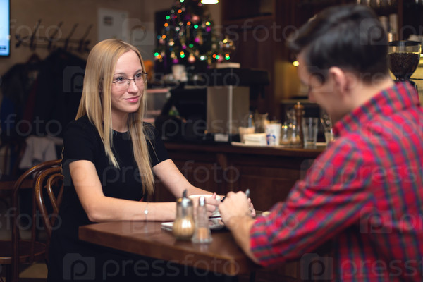 Young couple having a date in cafe drinking coffee staring at each other