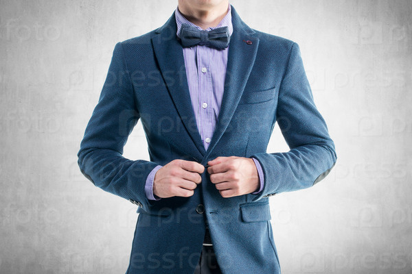 Handsome elegant young fashion man in coat tuxedo classical costume suit and bow tie