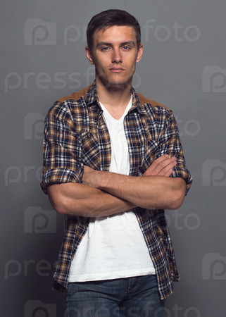 Portrait of a handsome young man - student urban casual style, checkered shirt, arms crossed