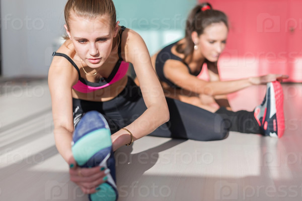 Group of fit women working stretching leg muscles of back to warm up at gym fitness, sport, training and lifestyle concept