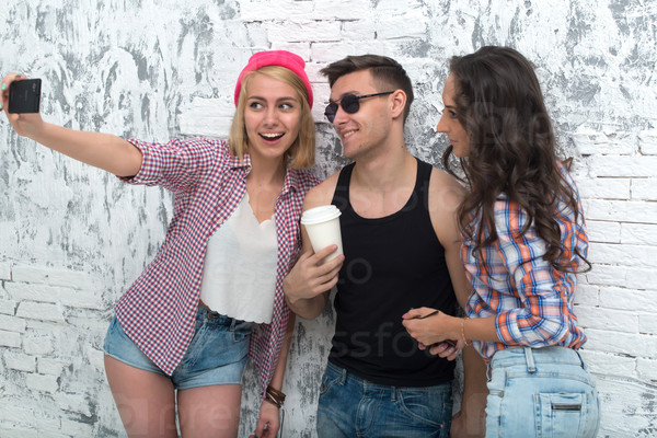 two women and man friends taking selfie together wearing summer clothes jeans shorts jeanswear street urban casual style having fun.