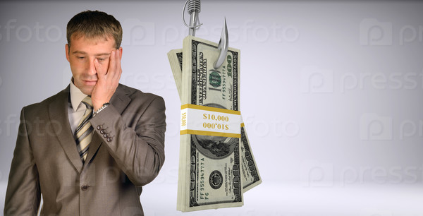 Sad businessman looking down with bundle of money on fish-hook on isolated grey background, stock photo