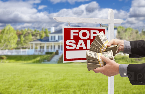 Man Handing Over Thousands of Dollars in Front of House and Sold For Sale Real Estate Sign.