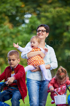 Family portrait outdoor in park. Modern mom with kids. Child learning to ride bike