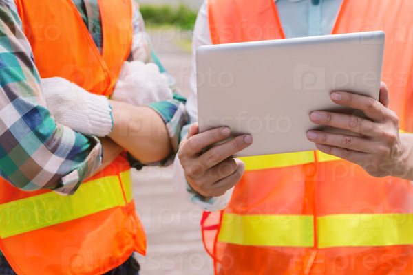 Cropped image of contractor sharing information on the digital tablet with a worker