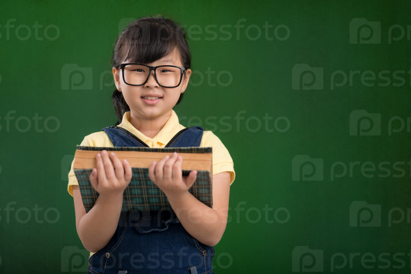 Portrait of Vietnamese schoolgirl holding a big book
