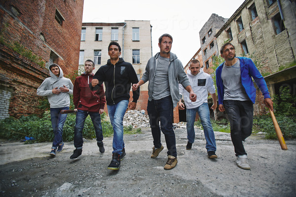 Group of spiteful hooligans walking along grunge brick houses