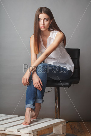 beautiful brunette fashion model posing at studio, sitting on chair