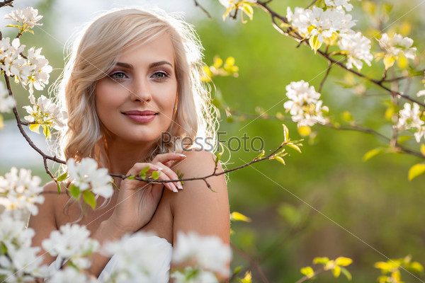 beautiful blonde woman head and shoulders portrait in a flowered spring garden