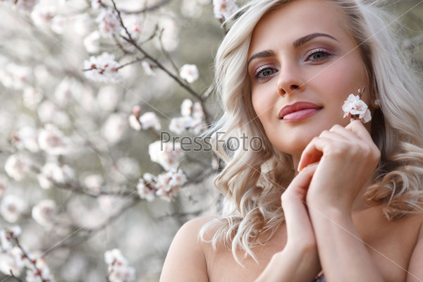 beautiful blonde woman head and shoulders portrait in a flowered spring garden