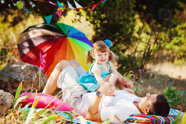 Happy young family with child resting outdoors in summer park