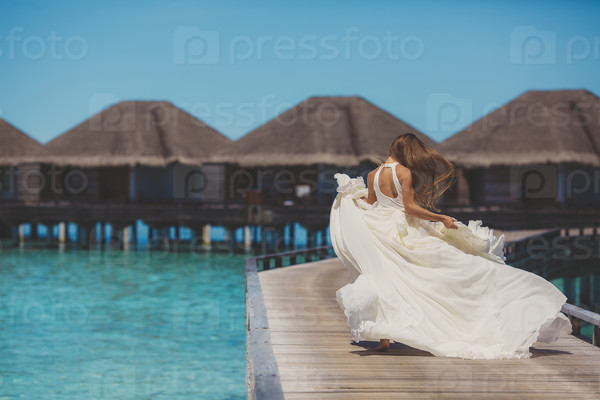 bride in wedding dress running and having fun on tropical island of maldives