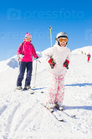 Happy smiling girl in ski goggles and a helmet with his mother, Zellertal, Austria. Vertical view