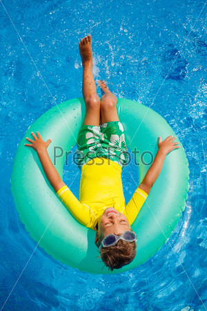Little boy floating on swim ring in pool