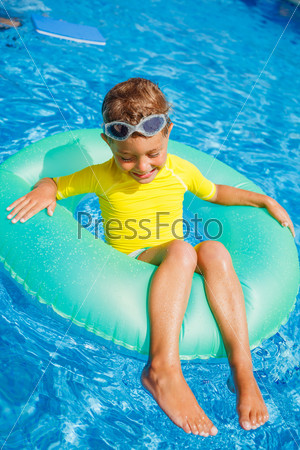 Little boy floating on swim ring in pool
