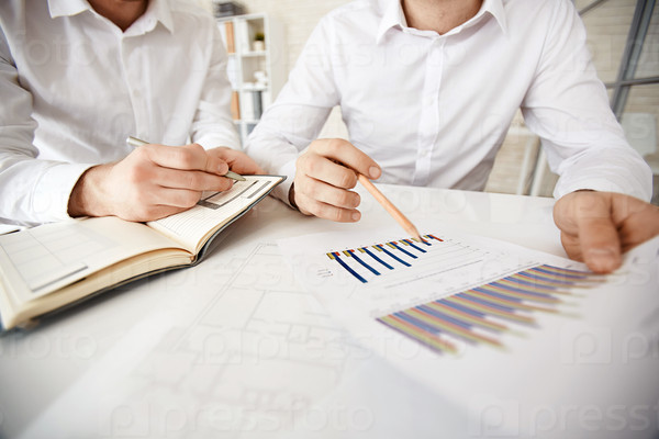 Group of businessmen explaining chart and making notes, stock photo