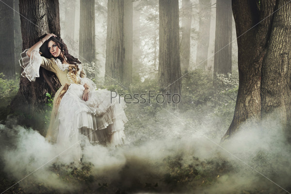 Fine art photo of a gorgeous lady in a mysterious foggy forest