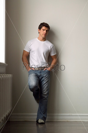 Young man leaning against white wall