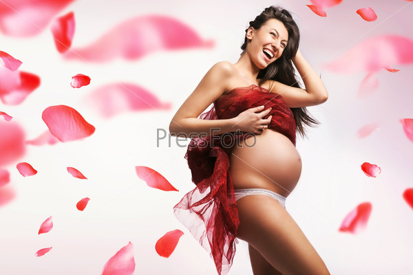 Young pregnant lady over flying rose petals