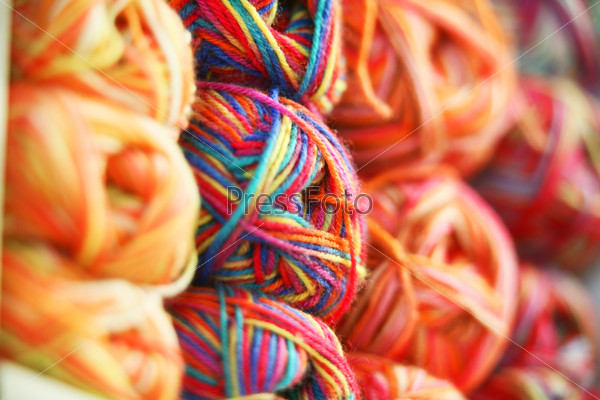 Multicolored wool rolled into balls in the shop, closeup