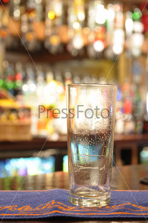 empty pint glass of beer sitting on bar in a pub