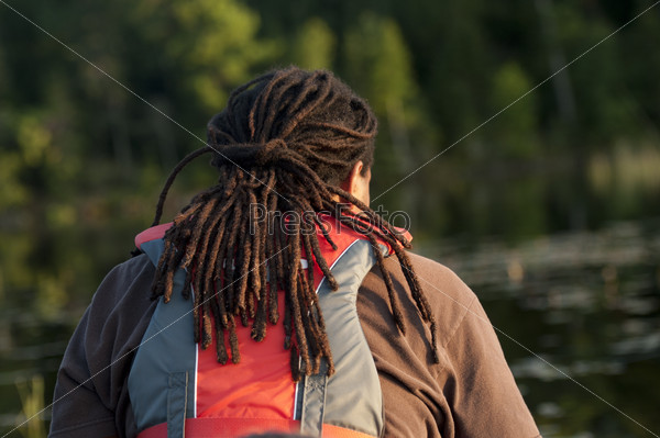 Back view of a man with dreadlocks wearing a life jacket at Lake of the Woods, Ontario