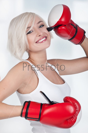 Cheerful blond woman doing make up in boxing gloves