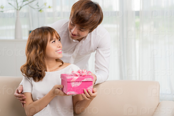 Young man giving a birthday present to his beautiful wife