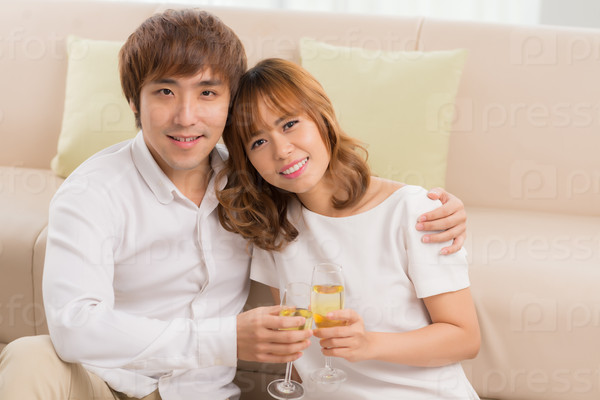 Romantic Asian couple hugging and drinking champagne at home